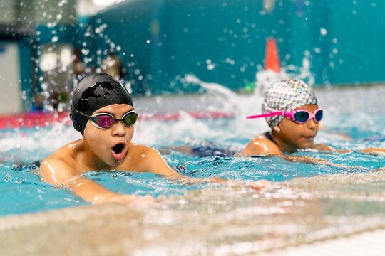 Children learning swimming techniques in indoor pool lesson
