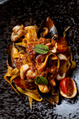 Steaming plate of seafood pasta showcases a rich blend of shrimp, mussels, and fresh tomatoes, all tossed in a savory tomato sauce. Perfect for a cozy dinner on a chilly evening