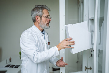Fototapeta premium Male doctor selecting medical supplies from cabinet