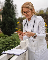 Doctor woman using smart phone outside healthcare facility