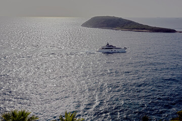 Luxury yacht cruising on shimmering blue waters near a small green island off the coast of Palma de Mallorca. sea, travel