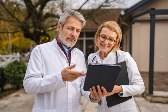 Healthcare professionals discussing outdoor patient chart during consultation