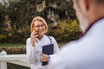 Senior doctor smiling having phone call outdoors