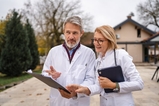 Healthcare professionals discussing outdoor patient chart during consultation - Powered by Adobe