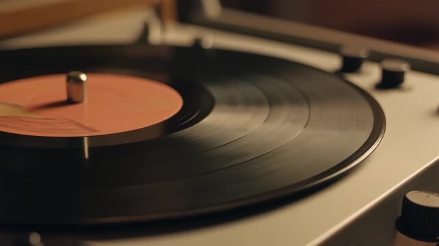 A close-up shot of a vintage record player with a black vinyl record spinning, featuring an orange label.
