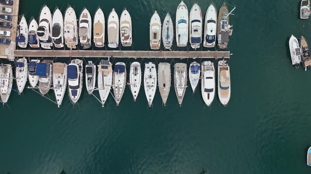 Tilt-down aerial view of docked boats and yachts at Msida Marina in Malta, revealing the geometric arrangement of vessels over calm Mediterranean waters from directly above.