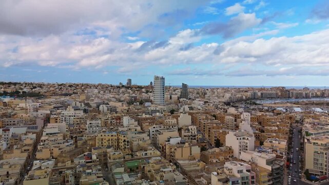 Drone orbital shot above Msida, Malta, showcasing the coastal skyline of Ta&rsquo; Xbiex, Gżira, and Sliema with urban buildings, modern towers, and Mediterranean harbor views.