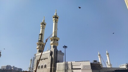 Obraz premium Sunny Low Angle Masjid al-Haram Minaret Under Construction Against Blue Sky