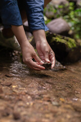 Woman Washing Hands in a Clear River in Lush Forest
