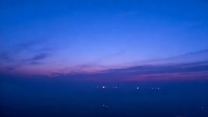 Twilight sky with soft purple and blue hues over a distant horizon with faint city lights