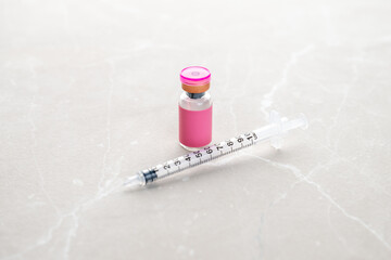 Single Use Syringe Next to Small Pink Glass Vial