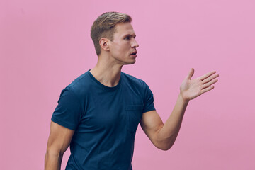 Serious focused young caucasian man wear blue t-shirt gesturing talking in video call digital communication concept isolated pink background studio portrait