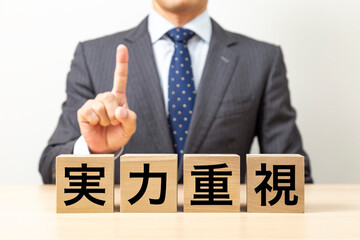 Obraz premium 「実力重視」と書かれたブロックとビジネスマン