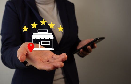 Five-star review of a store. A businesswoman holds her cell phone and in her hand displays a five-star store icon.