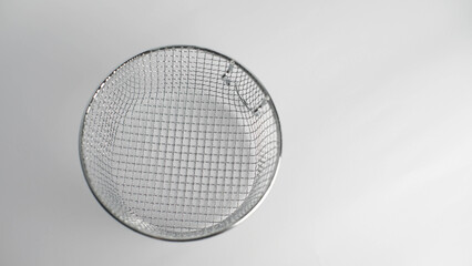 Overhead view of a clean, round metal mesh strainer on a white background, highlighting its intricate grid pattern and metallic texture. Ideal for various design uses.