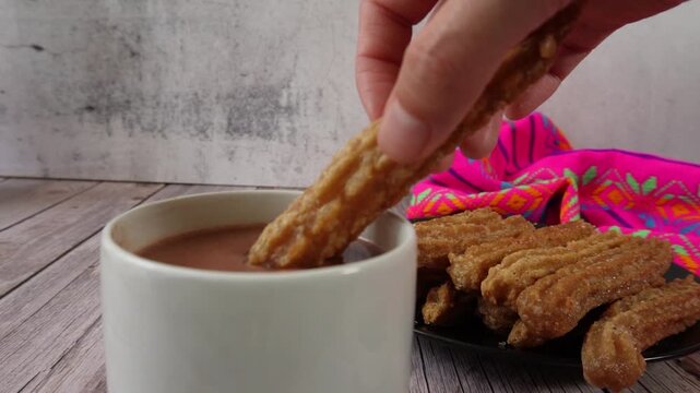 Slow motion of dipping a churro in hot chocolate. Mexican food