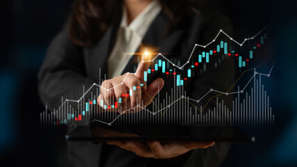 A business professional engages with digital stock market data on a tablet, illustrating modern analytics and financial trends in a sleek office space. Scalp