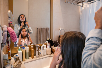 A woman is brushing her hair in front of a mirror