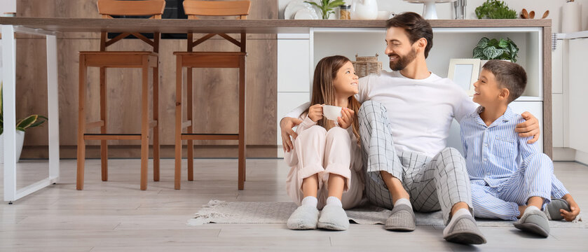 Happy father hugging his children on floor in kitchen