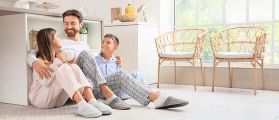 Happy father hugging his children on floor in kitchen