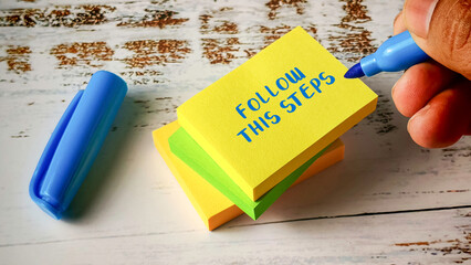 Follow This Steps Instructions Concept with Hand Writing on Stacked Colorful Sticky Notes