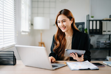 Business woman using tablet and laptop for doing math finance on an office desk, tax, report, accounting, statistics, and analytical research concept in office