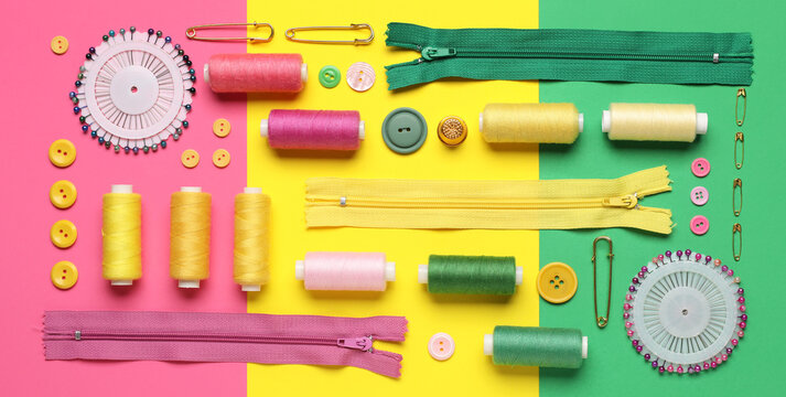 Composition with thread spools, zippers, ball pins and buttons on color background