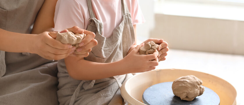 Little girl with her mother making ceramic pot at home - Powered by Adobe