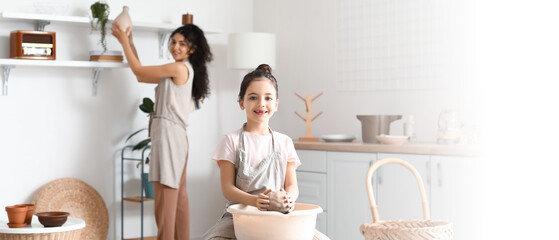 Little girl with her mother making ceramic pot at home
