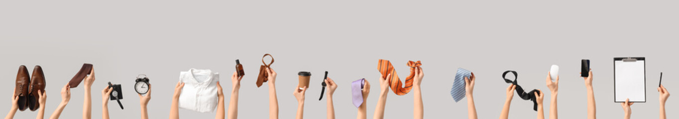 Hands holding man's businessman's accessories on grey background