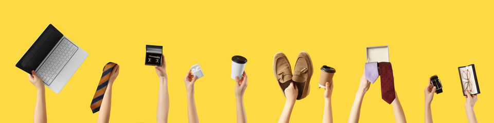 Hands holding man's businessman's accessories on yellow background