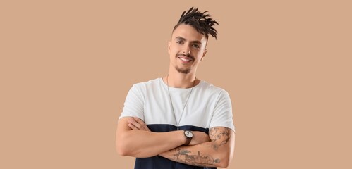 Happy young man with dreadlocks on beige background