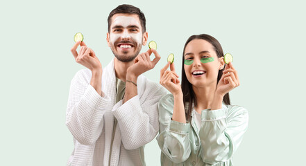 Young loving couple with cucumber slices on green background