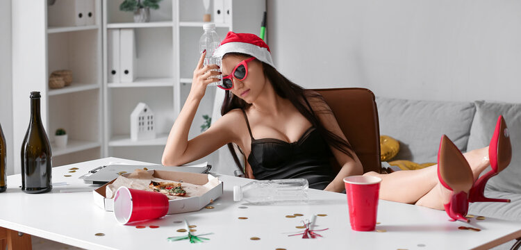 Drunk young woman sitting at table in office after New Year party