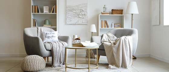Interior of light living room with cozy armchairs and books on coffee table © Pixel-Shot