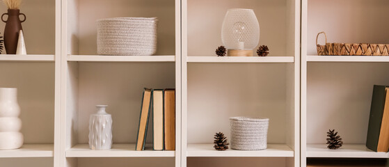 White bookshelves with books, pine cones and decor © Pixel-Shot