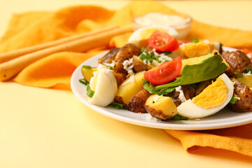 Plate of tasty potato salad with eggs and tomatoes on beige background, closeup