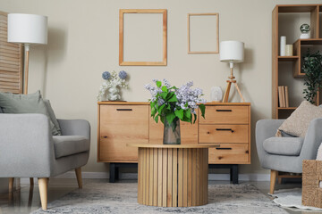 Table with flowers in vase, sofa and chest of drawers in interior of stylish living room