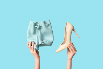 Female hands with bag and heeled shoes on blue background
