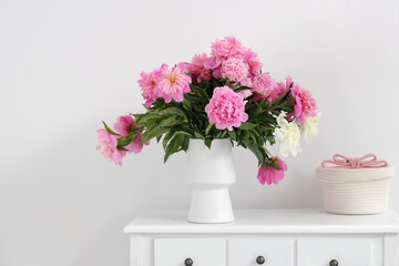 Table with beautiful peony flowers in vase in living room