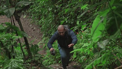 A man walks through a dense forest taking photos of the scenery, highlighting exploration, calmness, and connection with nature.