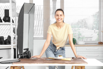 Young female photographer near table with food in kitchen