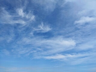 Obraz premium Clear blue sky with a few clouds. The sky is very bright and the clouds are scattered throughout in summer season 