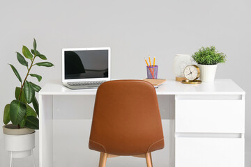 Stylish table with laptop and houseplant on white background