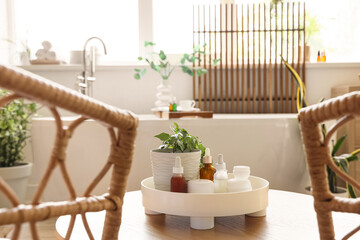 White bathtub and coffee table with cosmetic supplies in stylish bathroom