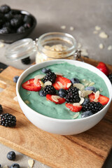 Bowl of tasty spirulina smoothie on grey grunge background