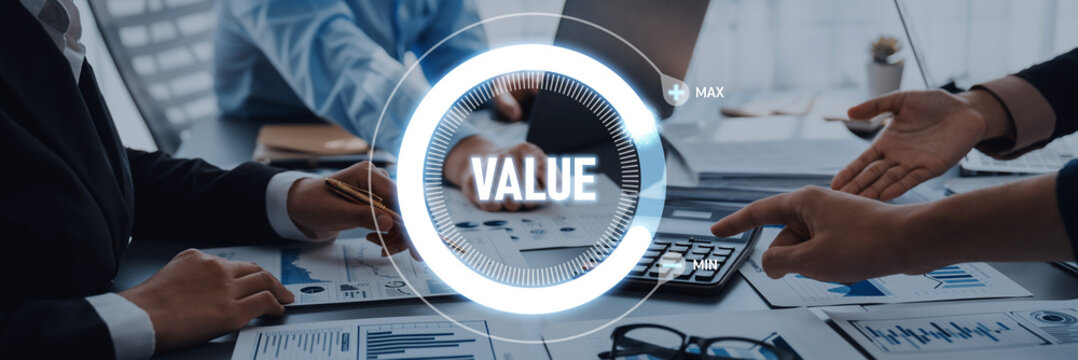 A team of professionals engaged in a business meeting, discussing value creation and financial strategies. Documents, charts, and technology highlight collaboration and decision-making. Trope