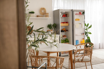 Modern kitchen interior with houseplants and open fridge full of fresh food