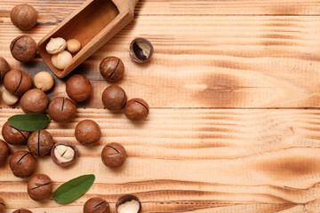 Scoop with tasty macadamia nuts on wooden background