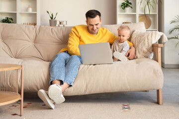 Father with his son and laptop sitting on sofa at home